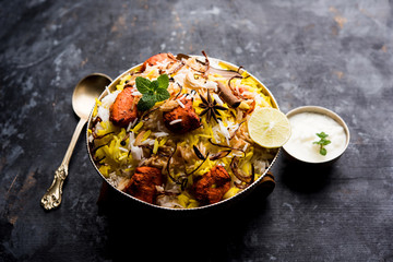 Indian Chicken Tikka Biriyani served in a bowl with yogurt. selective focus