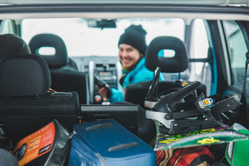smiling woman sitting in car. snowboard in car trunk. road trip