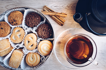 flat lay of Danish butter cookies with a cup of tea and kettle, iron, dry leaves and cinnamon