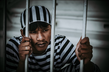 Portrait of Asian men desperate to catch the iron prison,prisoner concept,thailand people,Hope to...