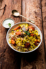 Indian Chicken Tikka Biriyani served in a bowl with yogurt. selective focus