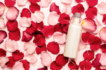 Bottle with natural cosmetic product on a background of rose petals. Spa concept