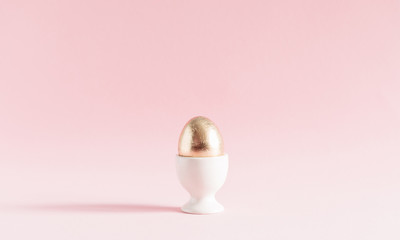 Easter gold egg on pastel pink background. Easter, spring concept. Copy space, banner