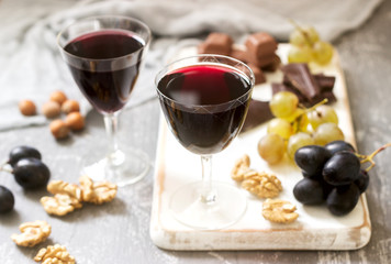 Creme de Cassis homemade liqueur served with grapes, nuts and chocolate. Rustic style.