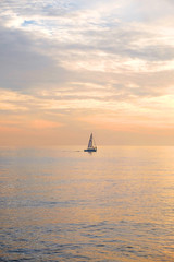 A sailing boat silhouetted in a calm seamless orange glowing sea