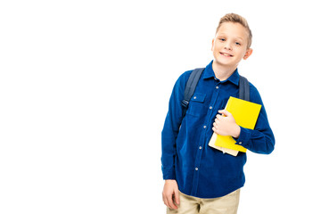 schoolboy in blue shirt with backpack holding books while looking at camera isolated on white