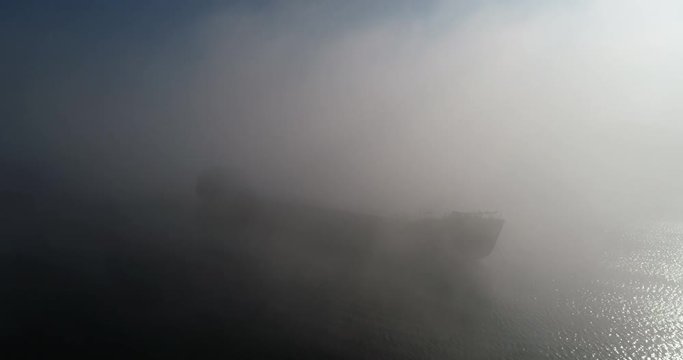 A huge barge on the river Dnipro in the morning fog with a visible silhouette of the buildings and city in the background (shot from the air) in 4K 5