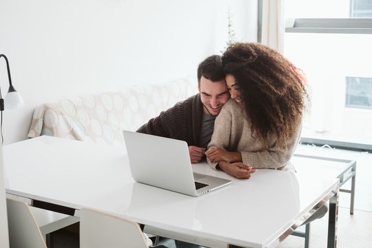 Cheerful multiethnic couple using laptop together