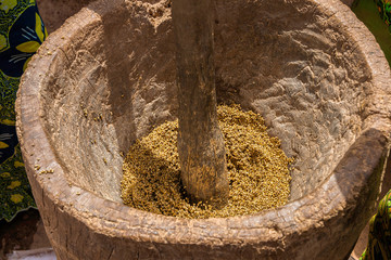 Close-up of a woman crushing cereals like millet with a wooden mortar and pestle, West Africa,...