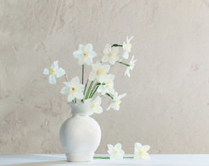 white narcissus in vase on wooden table