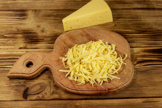 Grated cheese on cutting board on wooden table