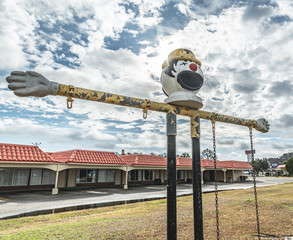 A broken down old children's swing set with a clown head in a derelict motel