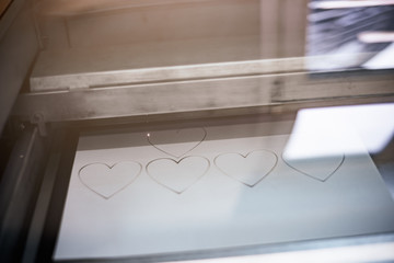 Laser engraving machine cutting hearts from paper