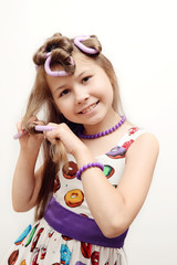 Portrait of a funny little girl with hair curlers. Pin-Up. On a white background.