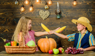 Fototapeta premium Kids girl boy celebrate harvest festival rustic style. Celebrate harvest festival. Children play corncobs vegetables wooden background. School festival holiday. Elementary school fall festival idea