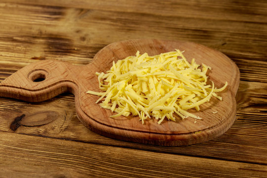 Grated cheese on cutting board on wooden table