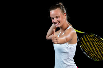 Female athlete posing with tennis racket against black background