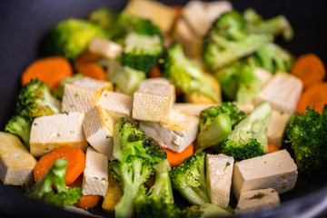 Grilled tofu with broccoli and carrots inside wok.