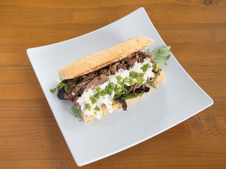 Mediterranean style beef gyro sandwich with creamy Greek sauce and arugula.