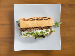 Mediterranean style beef gyro sandwich with creamy Greek sauce and arugula.