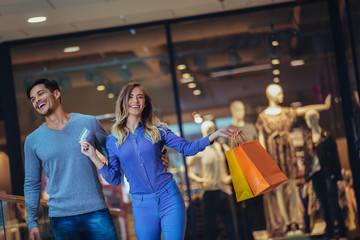 Portrait of a happy couple showing their new credit card at the mall