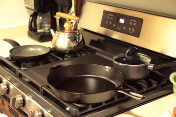 Modern stainless steel gas stove oven with cookware in a home.
