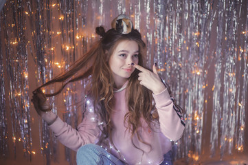 Obraz premium gentle and beautiful young girl on the background of garlands and tinsel with Guinea pig