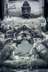 Fototapeta na wymiar Traditional balinese stone sculpture of a man and woman with moss