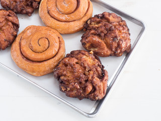 Apple fritters and cinnamon buns. Delicious sweet treats served in a bakery. Sugar filled breakfast items from a donut shop. 