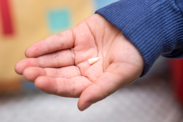 The child holds a fallen tooth on the palm of his hand. Milk tooth on the palm. First tooth lost