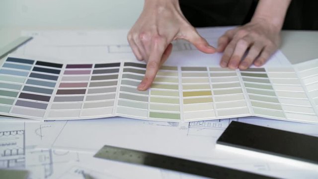 Interior designer selects wall paint samples. Designer at work. Architect desk. Decoration. Design project blueprints. Plans and drawings. Grey stone. Decorative material. Flatlay