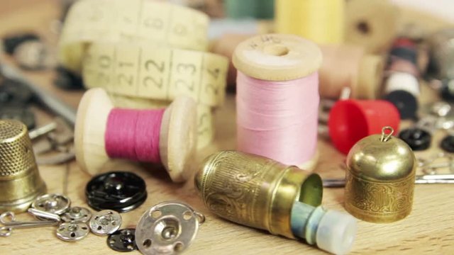 Various antique accessories and tools for hand sewing. Bronze and steel thimbles, bronze travel case for sewing accessories, buttons, hooks, needles