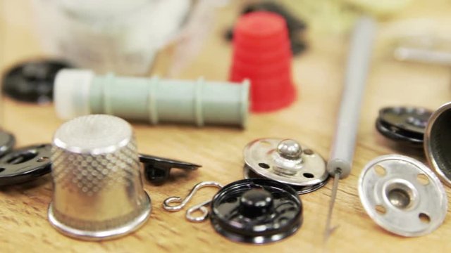 Various antique accessories and tools for hand sewing. Bronze and steel thimbles, bronze travel case for sewing accessories, buttons, hooks, needles