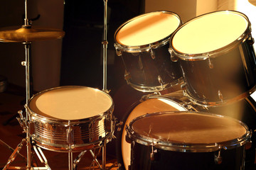 Drum set illuminated by the rays of the setting sun in a music studio. Closeup.