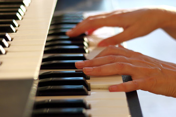 Fototapeta premium Woman's hands on the keyboard of the piano (electronic organ) closeup. Hands musician playing the piano. Hands pianist playing music on the piano. Musical education concept.