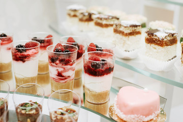 Different fruit desserts with fruits in glasses on the table. Restaurant presentation, food, party concept