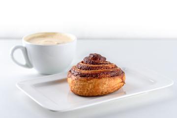 Cup of coffee and cinnamon roll bun pastry over the white background