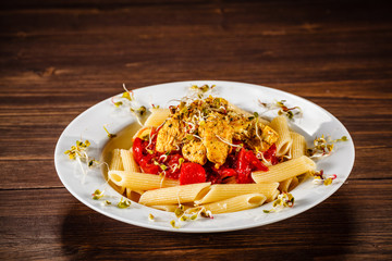 Pasta with chicken meat and sauce on wooden background