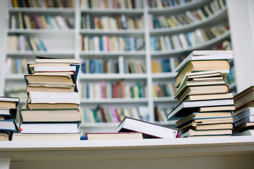 Stacks of paperback books, closeup, with the full bookshelf in the background. Searching for the right book in a bookstore. Piles of bestsellers.
