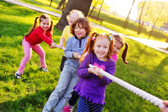 Children play tug of war in the park. Children's Day, June 1, friendship, childhood, vacation, camp