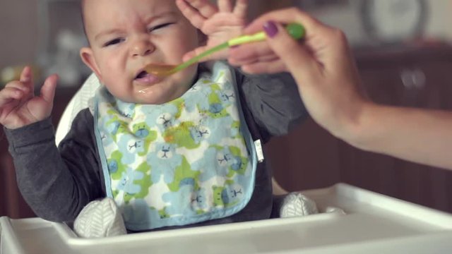 Cute baby does not want to eat her food spoon fed mother problem solids slow motion