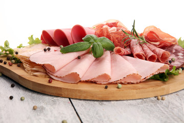 Food tray with delicious salami, pieces of sliced ham, sausage and salad. Meat platter with selection.