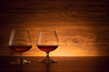 The two brandy glasses on a wooden background. Cognac on the table