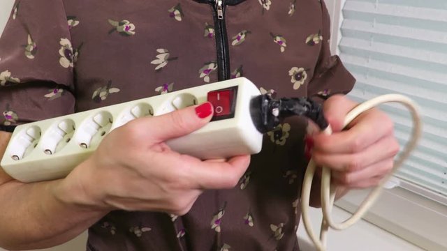 Woman checking old and unsafe power strip