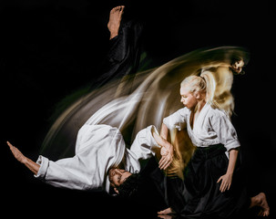 two bodokas fighters man and woman practicing Aikido studio shot isolated on black background - obrazy, fototapety, plakaty