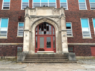 Old, abandoned school building in Indiana. Front entryway with broken windows.