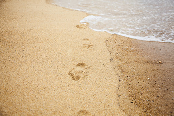 Footprints of bare feet on wet sand. Summer vacation on the beach. Walk along the sea shore