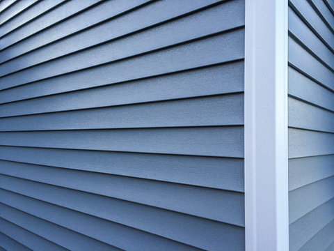 Blue vinyl siding with white trim on the outside wall of a new home