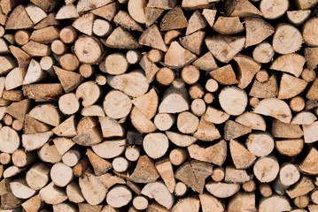 Stacked firewood for the heating season. Firewood stack wall. Wood texture background.