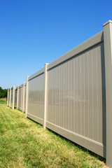 Tan colored vinyl fence in perspective with blue sky in the background